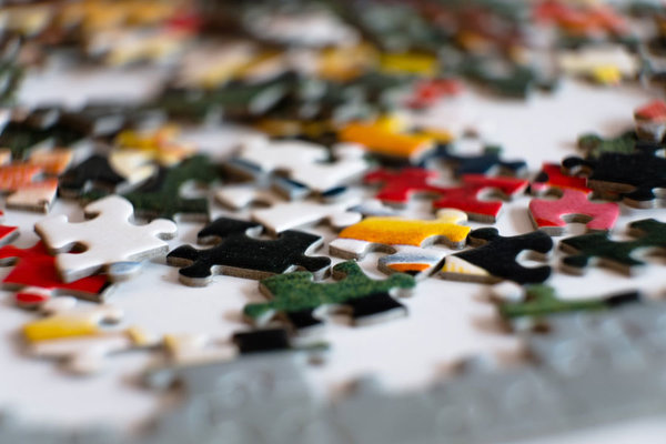 Bunte Puzzleteile in verschiedenen Farben liegen durcheinander auf einer Unterlage.